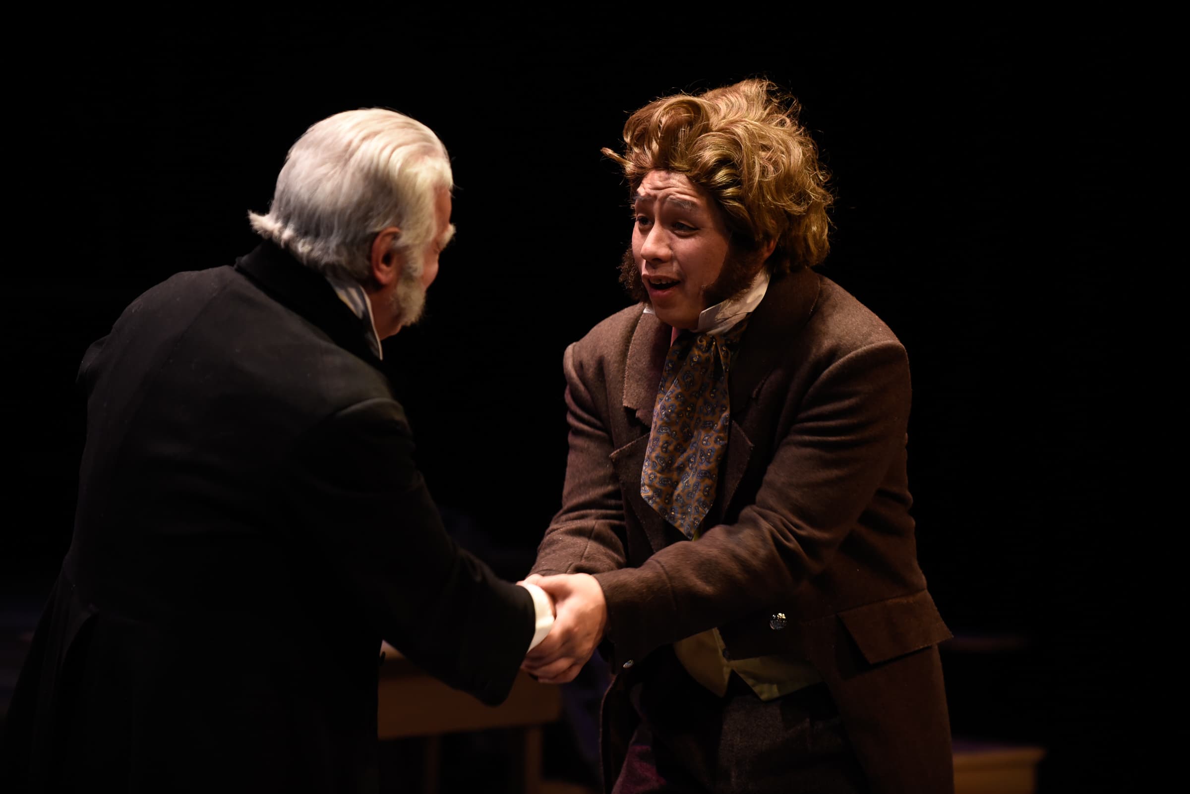 A scene from A Christmas Carol, where Scrooge is shaking hands with another man.