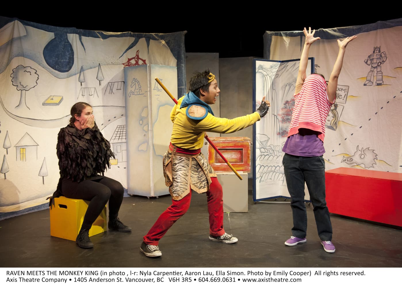 Three people are on stage. The one dressed as a raven has a look of shock on her face, the person dressed as the monkey king
seems to be doing magic on the third person.