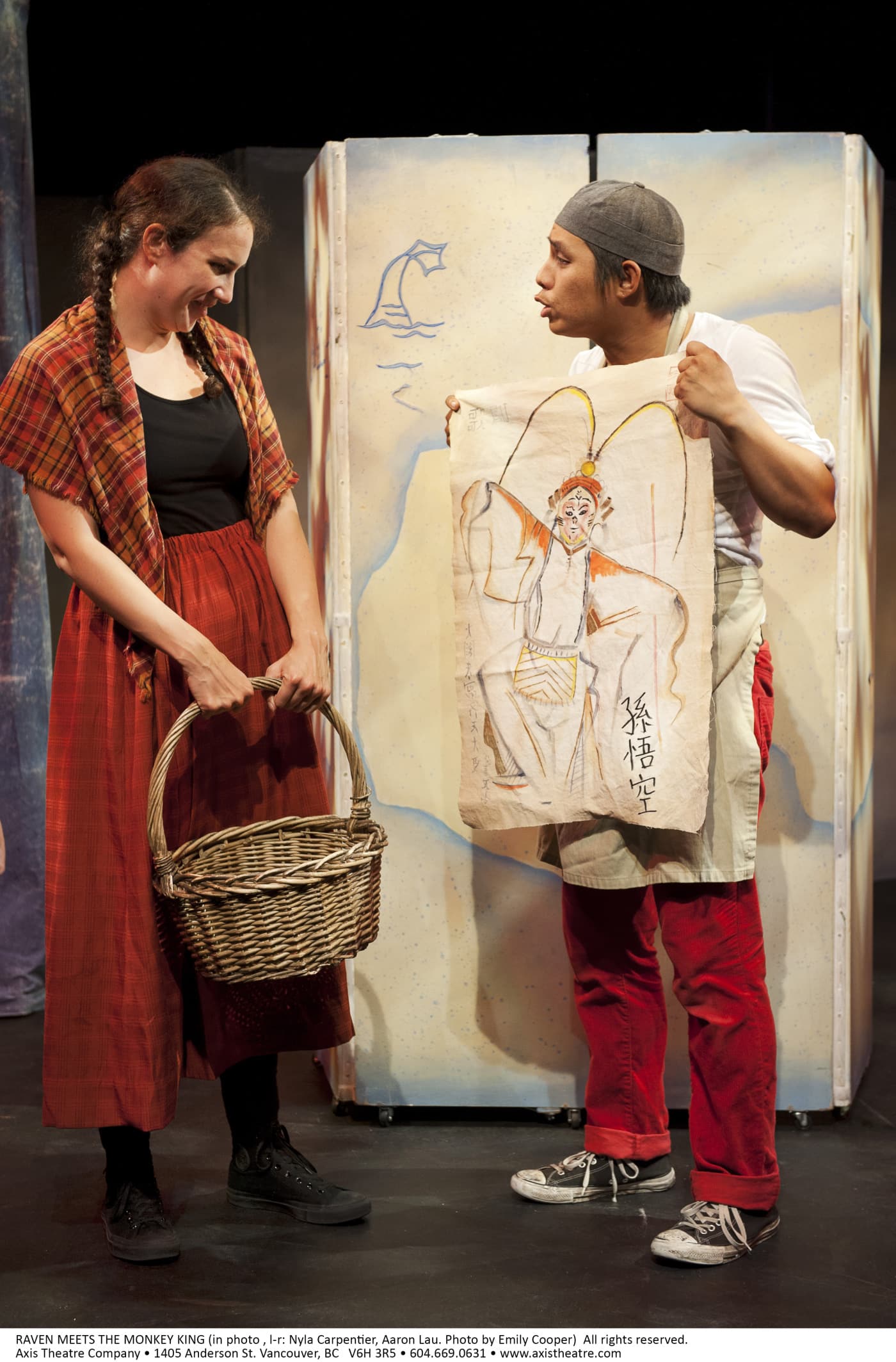 A woman is holding a straw basket and a man dressed in Chinese garb is showing her a painting of a monkey.